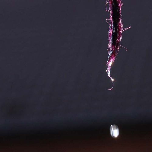 Einzelner Wassertropfen, der vom gefärbten Wollgarn abtropft.