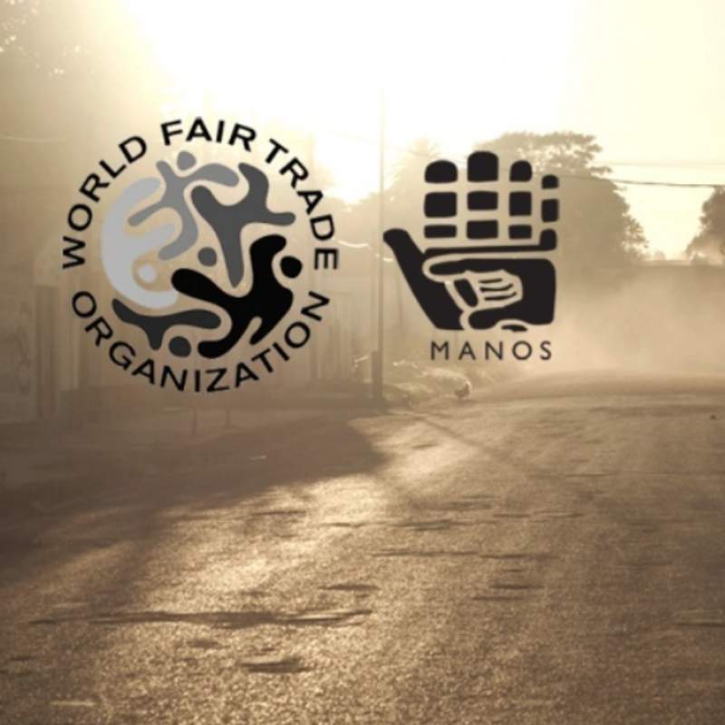 Vollbild Logo von manos del uruguay und world fair trade logo vor staubiger Straße