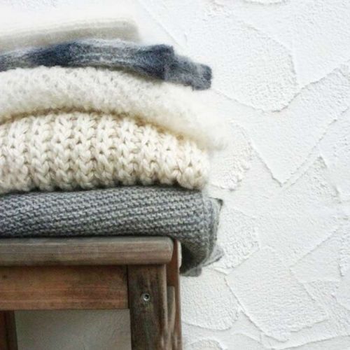 Ein Stapel handgestrickte Schals und Mützen in Naturtönen